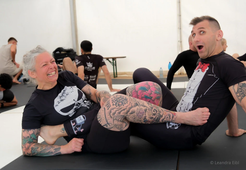 No-Gi Grappling Camp (Guerilla Grappling) – Beinverschlingung (Heelhook) im Training, zwei lachende Trainingspartner im Camp-Zelt